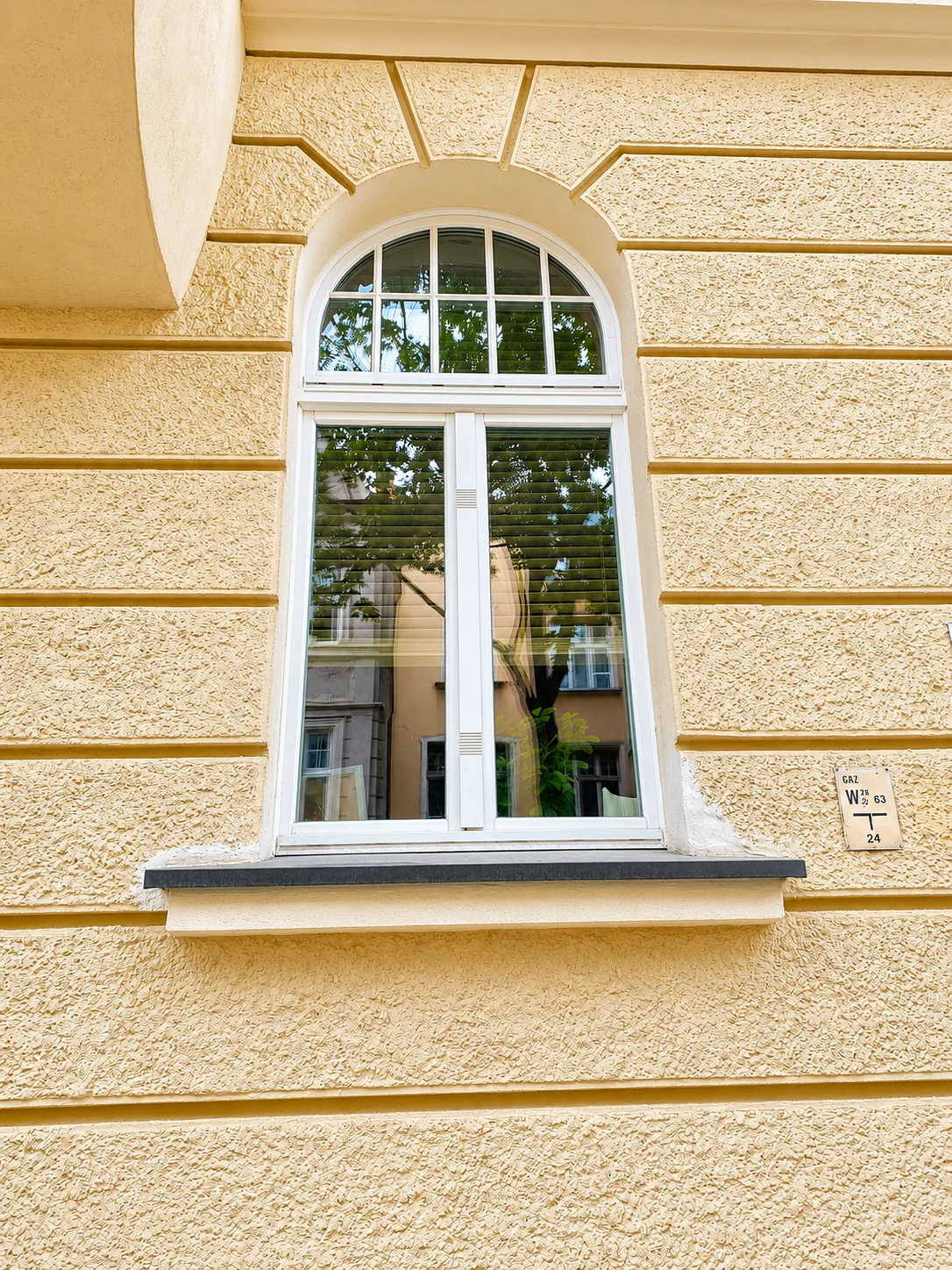 Białe okno drewniane łukowe ze szprosami w kamienicy Bydgoszcz – CARPENTER