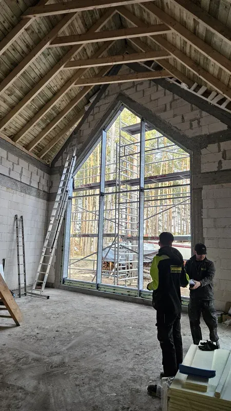 Ekipa CARPENTER przy wysokim przeszkleniu trapezowym wewnątrz domu
