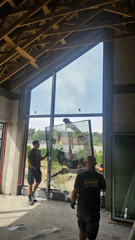 Ekipa CARPENTER przy dużej konstrukcji okiennej wewnątrz budynku