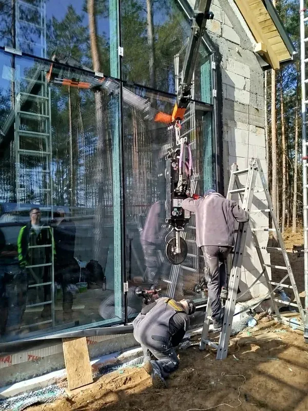 Monterzy ustawiają szybę w dużej konstrukcji przy użyciu chwytaka